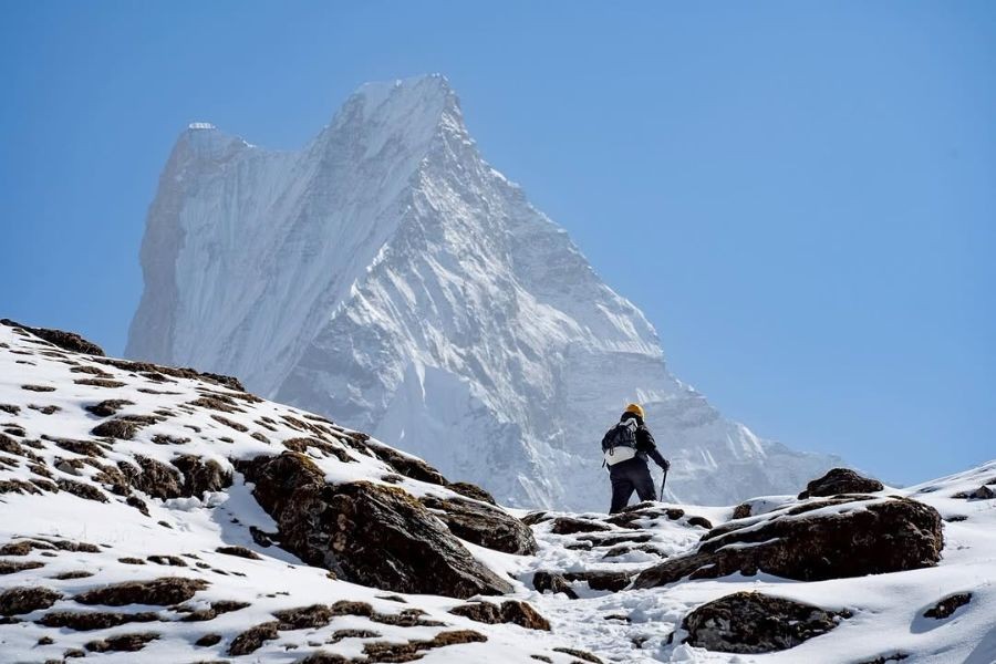 dventurer ascending a snowy trail toward the towering Mardi Himal.